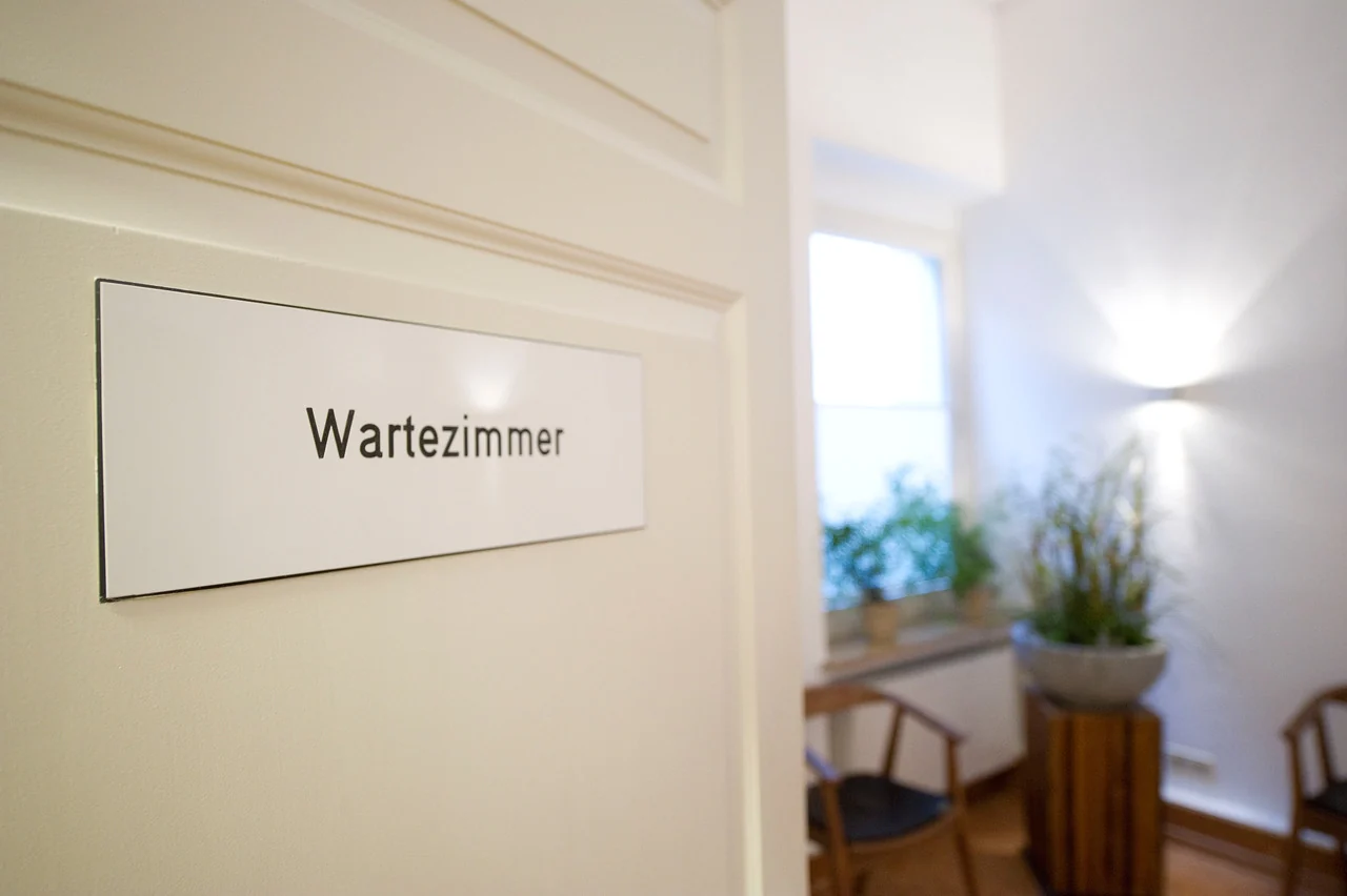 Das Schild Wartezimmer an der weißen Tür