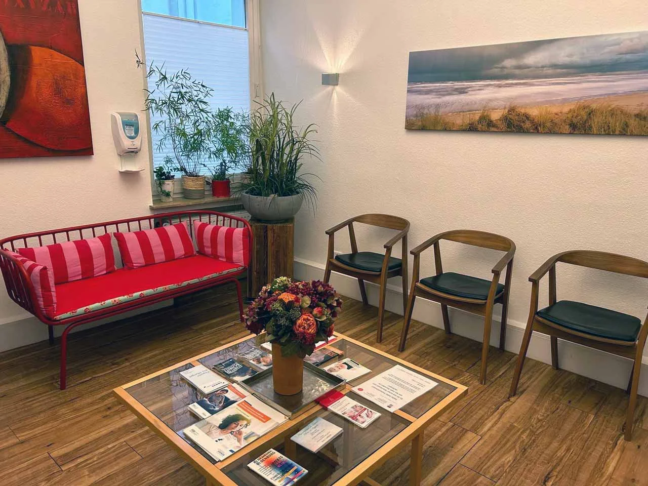 Das Wartezimmer mit roter Bank, Holzstühlen und Blumen auf dem Tisch