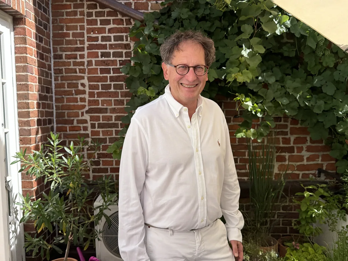Dr. med. Heiner Klingler im Innenhof vor Backsteinwand und Weinreben